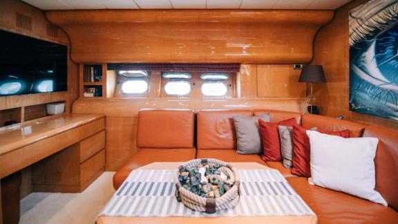 Zu sehen ist der Salon der Motoryacht Atrato in Athen mit Ledersofa, Fenstern und TV-Bereich.