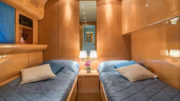 Zu sehen ist die Zweibettkabine der Motoryacht Atrato in Athen mit zwei Einzelbetten und Stauraum.