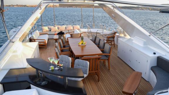 The upper deck features a bar, a large dining table, and cozy lounge seating—perfect for sunset gatherings.