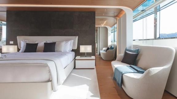Spacious bed, lounge chair and full-length windows in Dawo yacht’s master suite, docked in Sibenik.