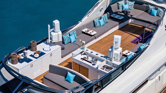 The flybridge of Dream motor yacht in Athens features lounge seating, a bar counter and open deck space.