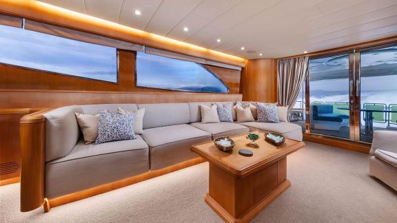 The lounge of Dream motor yacht in Athens features a large sofa, coffee table and sea-view glass doors.