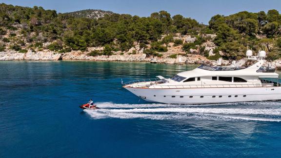 Dream motor yacht cruising in Athens, moving fast on clear waters with a jet ski alongside.