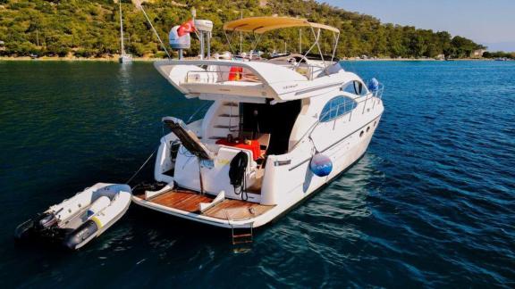 Heckansicht der Motoryacht Ela mit Beiboot auf blauem Wasser.