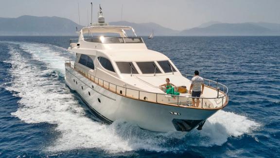 Off Athens the 4 cabin 10 guest motor yacht Estia Poseidon cruising. Guests relaxing on the foredeck at sea.