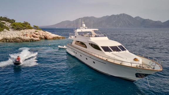 In an Athens bay the 4 cabin 10 guest motor yacht Estia Poseidon is anchored. Guests enjoy jet ski ride nearby.