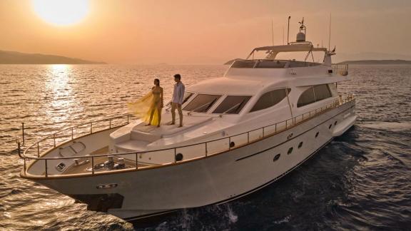 Off Athens at sunset the 4 cabin 10 guest motor yacht Estia Poseidon cruising. Guests enjoying the view on the foredeck.