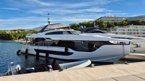 In Sibenik motor yacht charter option First Horizon docked at marina next to pier and other yachts.