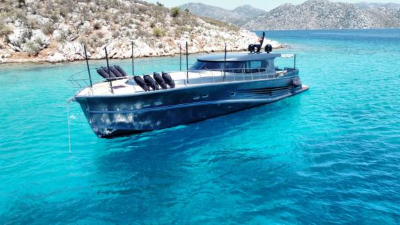 Motor yacht Fundamental B anchored in turquoise waters.