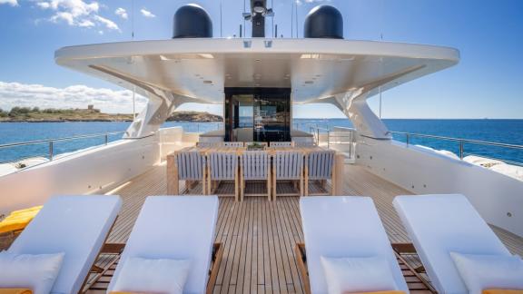 In Spain weekly yacht rental options Moka shows dining table and sun loungers with sea view.