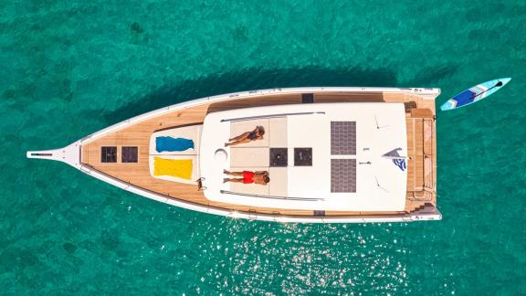 Anchored off Lavrion the 3 cabin 6 guest Omikron Yachts OT 60 N ice seen from above. Guests sunbathing on deck.