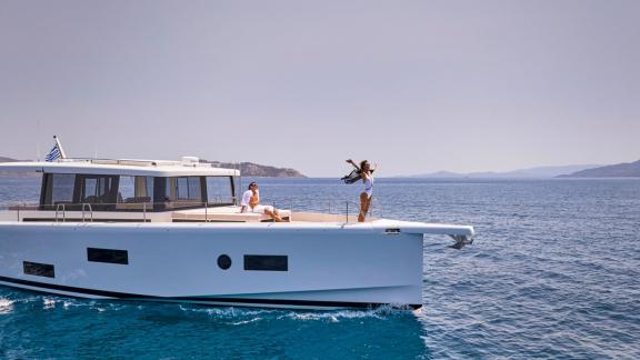 Off Lavrion the 3 cabin 6 guest Omikron Yachts OT 60 N ice motor yacht cruising. Guests enjoying the foredeck view.