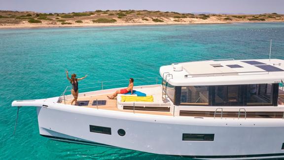 Anchored off Lavrion the 3 cabin 6 guest Omikron Yachts OT 60 N ice with guests sunbathing on the foredeck.