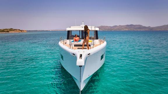 Anchored off Lavrion the 3 cabin 6 guest Omikron Yachts OT 60 N ice seen from front. Two guests relaxing on the bow.