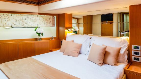 На яхте Ferretti 780 Orlando L уютная гостевая каюта с мягкой кроватью и светлым интерьером.