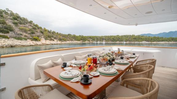 Anchored near Athens, the aft deck features a breakfast setup with scenic views of the bay.