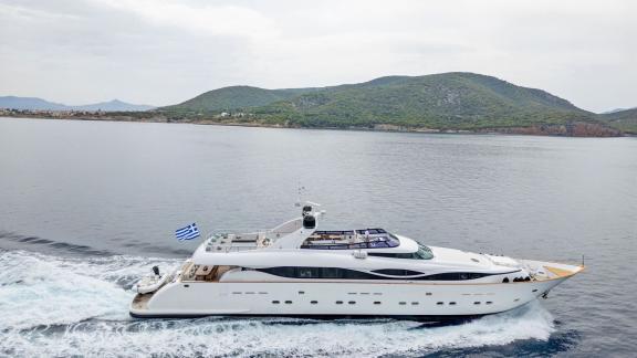 The luxury motor yacht Pareaki 2 is seen underway near Athens with scenic hills in the background.