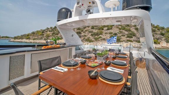 On the upper deck near Athens, the table is elegantly set for outdoor meals with sea views.