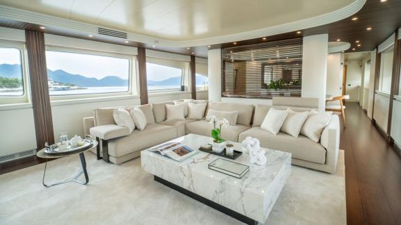 The saloon features a large sofa set, marble table and panoramic windows with sea views near Athens.