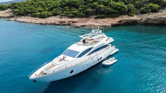 Die Motoryacht Red Rose liegt vor der Küste von Athen im türkisfarbenen Wasser mit Tenderboot in der Außenansicht.