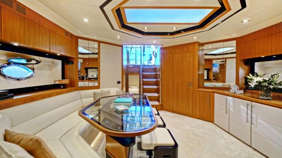 Im unteren Salon der Sea U Motoryacht stehen ein Glastisch, cremefarbene Sitze und ein achteckiges Deckendetail.