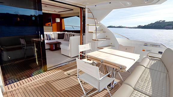 Among Nice yacht charter options Turquoise motor yacht shows aft deck with table seating and salon entrance.