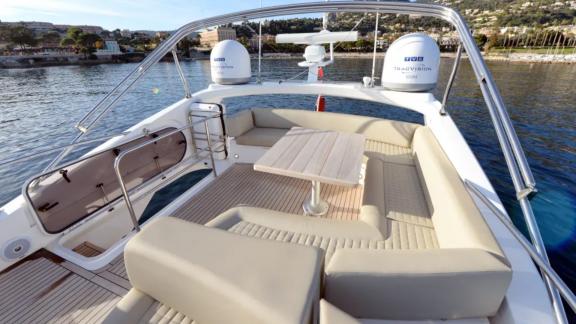 Among Nice yacht charter options Turquoise motor yacht shows upper deck with lounge seating and table.