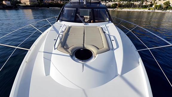Among Nice yacht charter options Turquoise motor yacht shows front deck with cushioned sunbathing area.