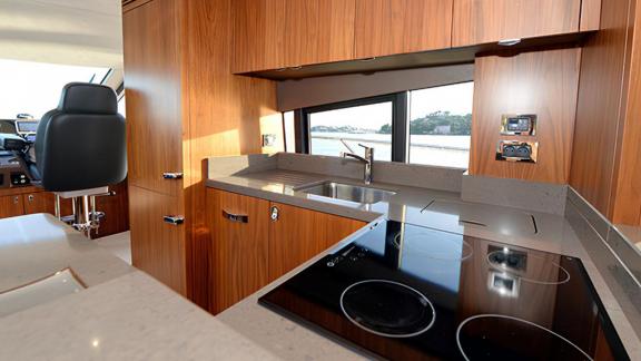 Among Nice yacht charter options Turquoise motor yacht shows galley with cooktop sink and countertop.