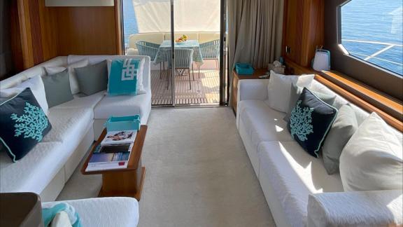 Among Nice yacht charter options Turquoise motor yacht shows lounge with sofas and access to outdoor deck.