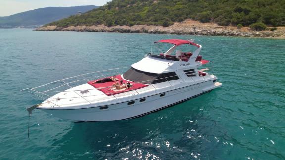 Motoryacht Uranos in der Bucht von Bodrum vor Anker, zwei Personen sonnen sich auf dem Vorderdeck.