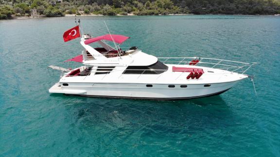 Motoryacht Uranos vor der Küste von Bodrum vor Anker, mit rotem Verdeck und Kissen.