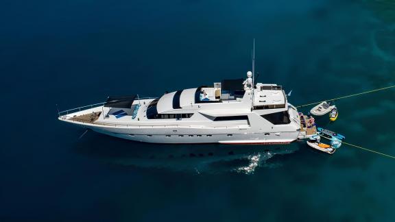 Wish Alfamarine 91 motor yacht is anchored in clear waters with a tender and water toys at the stern platform.