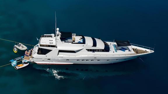 Wish Alfamarine 91 motor yacht is anchored in turquoise waters with water toys at the stern and sunbeds on the foredeck.