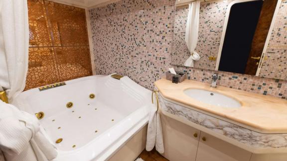 The bathroom of Wish Alfamarine 91 features a jacuzzi tub, sink unit and mosaic wall tiles.