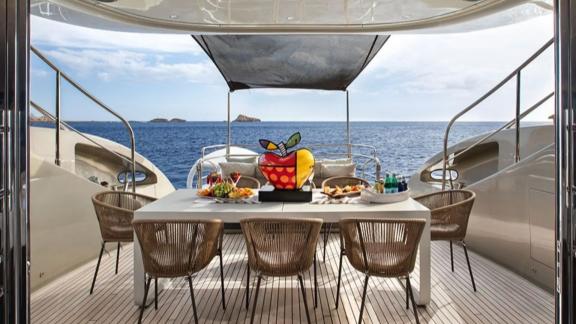 Among Mallorca yacht charter options Ycm120 shows dining table and seating with ocean view.