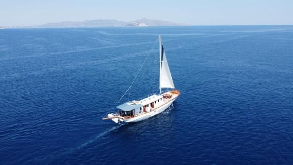 Cosmos motorsailer is cruising on deep blue waters with its sail raised.