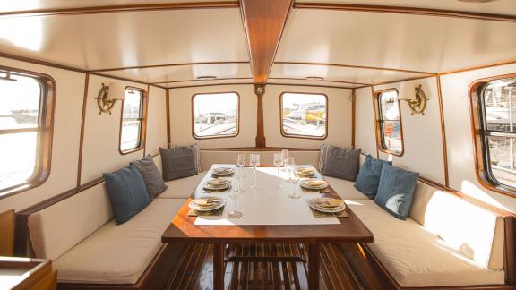 The interior salon of Cosmos features a cushioned seating area and a neatly set dining table.