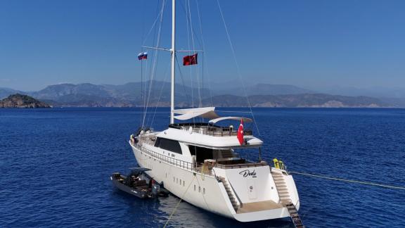Anchored off Fethiye the 6 cabin 12 guest Dodo motorsailer shown from stern with swim platform and tender.
