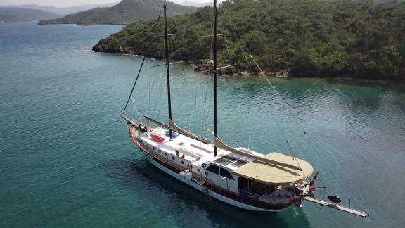 The Gulet Life is Life is anchored in clear turquoise waters, surrounded by lush nature.