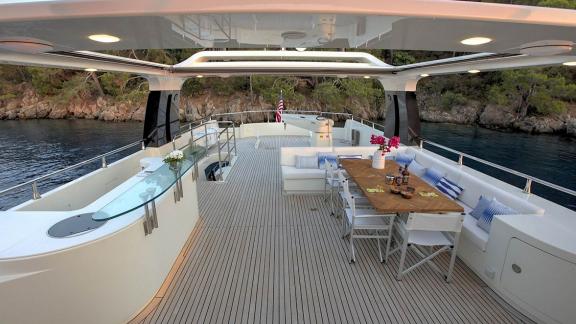 Archsea motoryatın üst güvertesinde yemek masası ve bar bölümüyle rahat bir akşam ortamı sunuluyor.