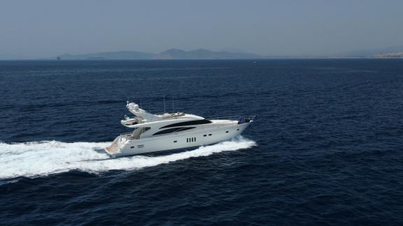 The yacht Azure is moving at high speed in the open sea, mountains visible in the background.