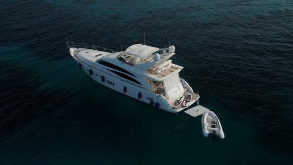 The yacht Azure is anchored in the open sea, with an inflatable dinghy beside it.