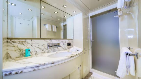 Located off Makarska, Cynthia’s bathroom features marble countertop and sleek glass shower enclosure.