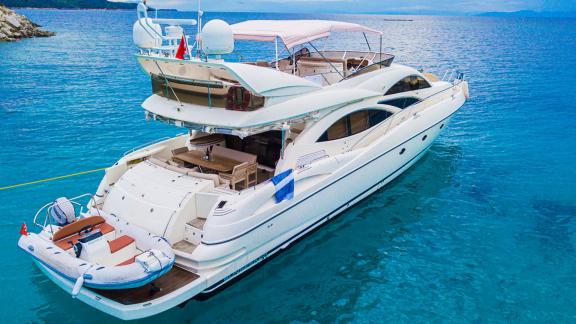 The Edition yacht anchored in calm turquoise waters with a mountain view in the background.