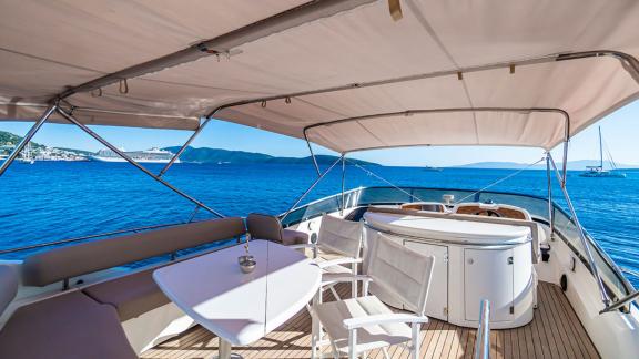 The flybridge of the Edition yacht offers a spacious seating area with a table and shade for a relaxing environment.