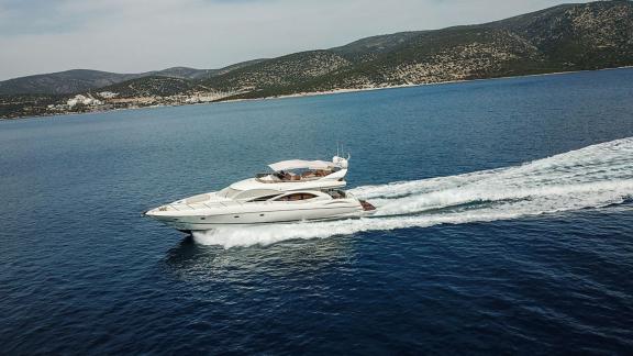 The Edition yacht swiftly cruises through the blue waters of the Aegean Sea with mountain views.