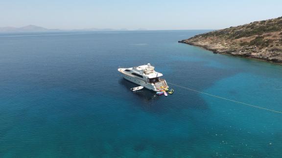 The Efmaria motor yacht anchored in turquoise waters near a coastline.