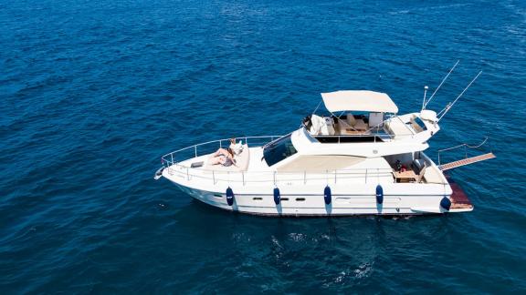 Die Motoryacht Free Day auf offener See, Gäste sonnen sich auf dem Deck. Rundherum blaues Meer.