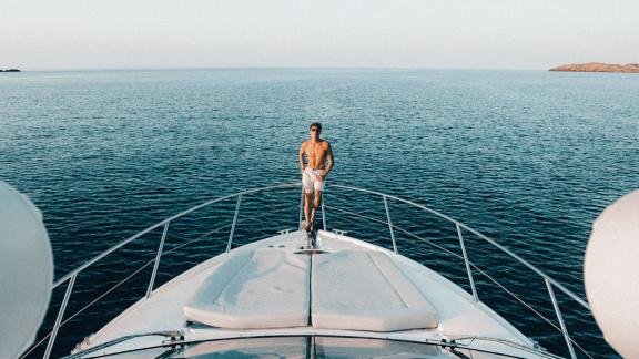 Ein Gast steht auf dem Vordeck der Yacht Funseeker und genießt das Meer und die Aussicht.